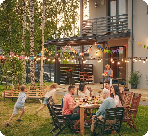 Family and friends gathered for an outdoor dinner in a garden at dusk